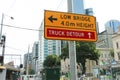 A yellow and black Ã¢â¬â¢Low Bridge, 4m HeightÃ¢â¬â¢ and Ã¢â¬ËTruck DetourÃ¢â¬â¢ sign near the Flinders Street rail bridge